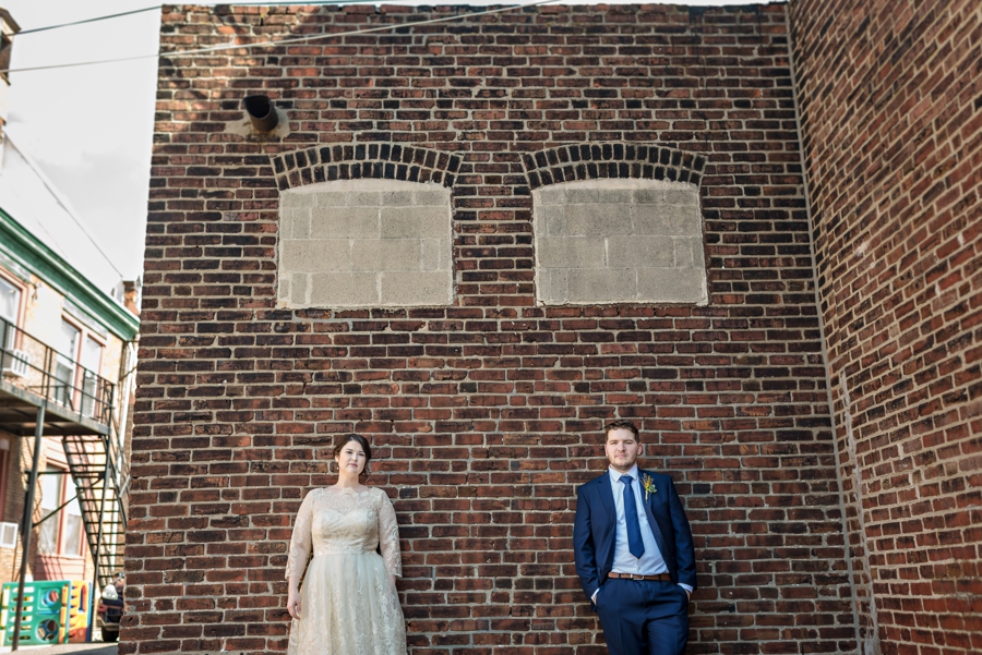 A bride and groom lean against a brick wall in Philadelphia.